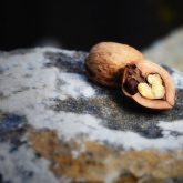 a cracked open walnut with a heart shaped center lying atop a rock