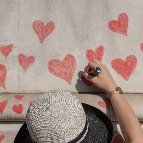 woman drawing red hearts on paper