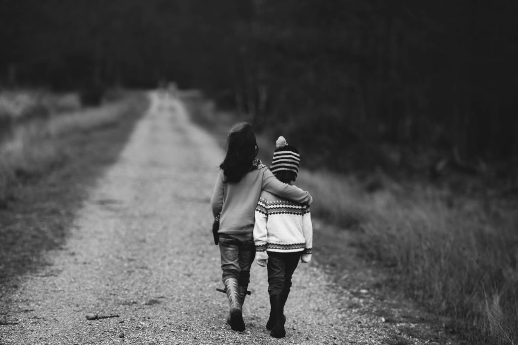 2 kids walking on a path arms around each other