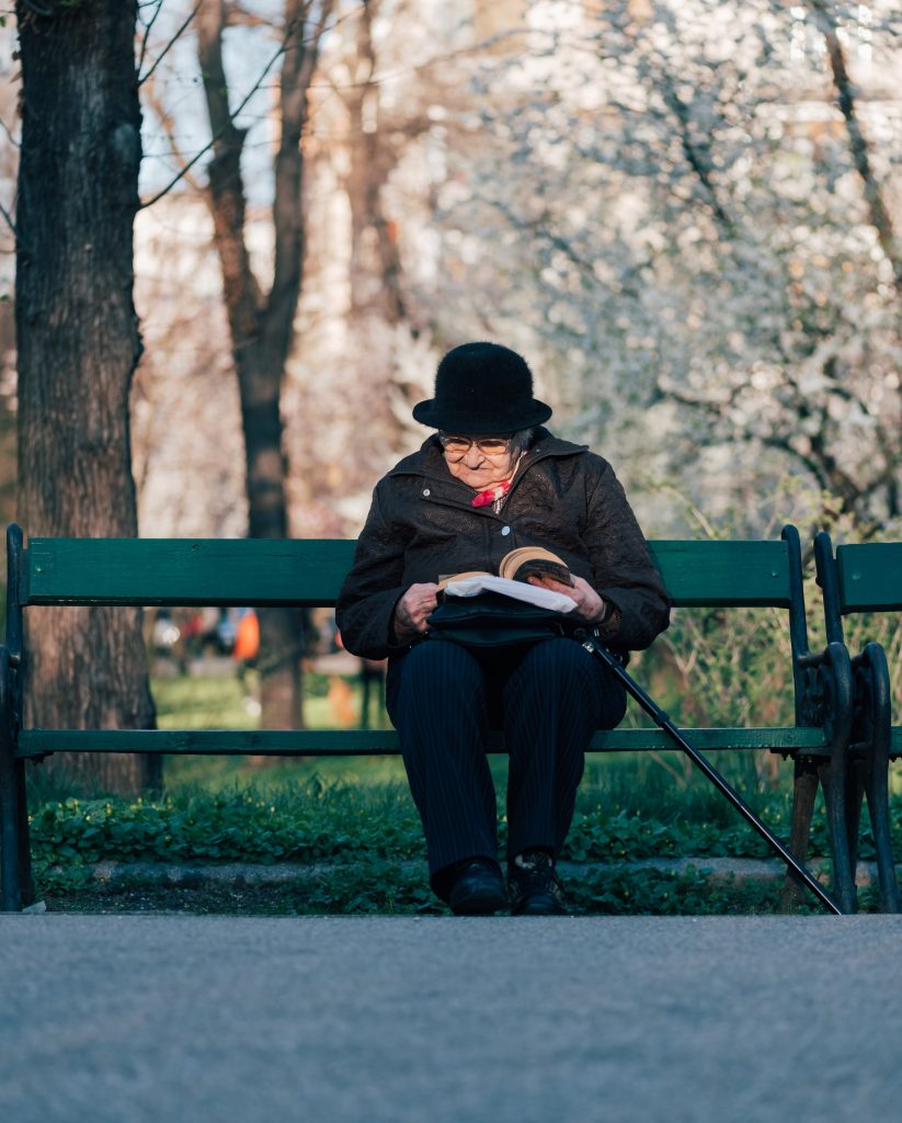 old woman reading on park bench